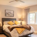 A comfortable looking bed in master bedroom with brown and yellow accents.