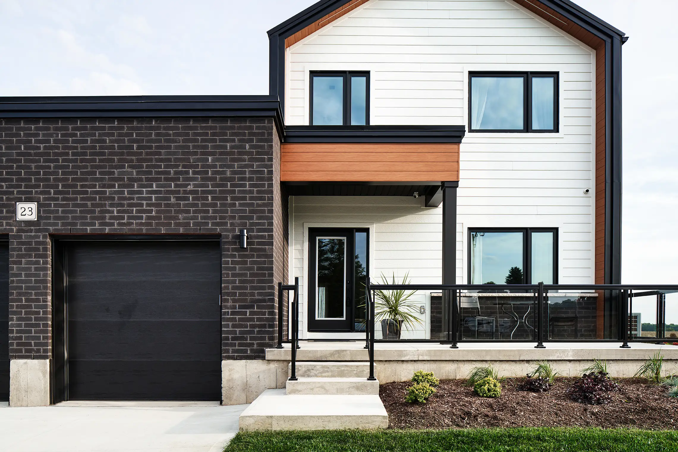 Brick garage with a black garage door beside a covered porch