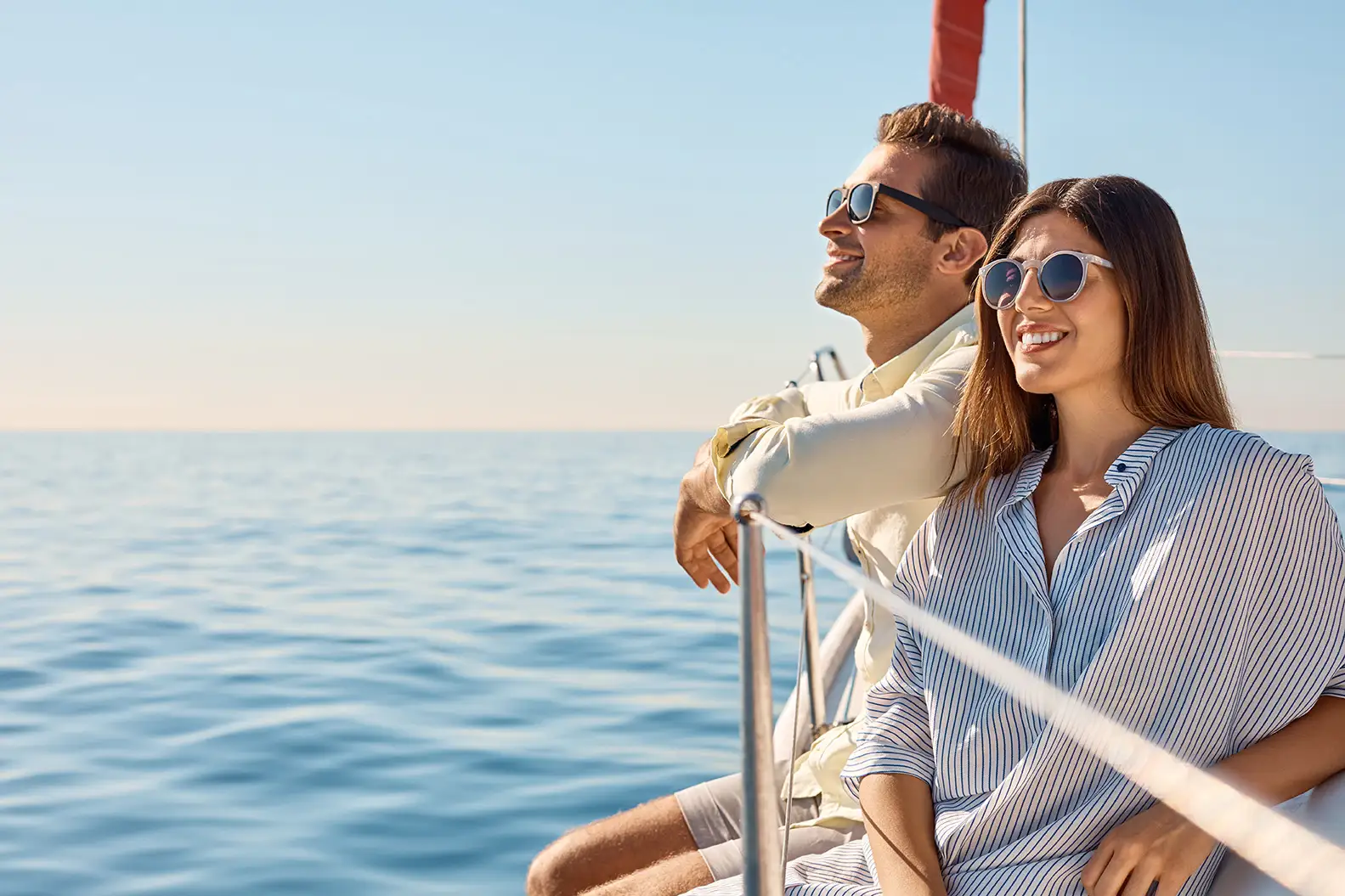 Smiling couple in sunglasses on the deck of a sailboat
