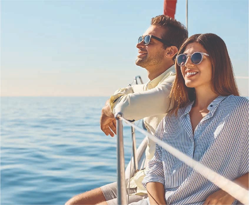 Smiling couple in sunglasses on the deck of a sailboat