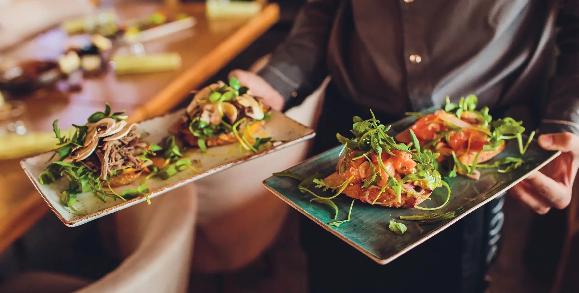 Server carrying two plates of bruschetta