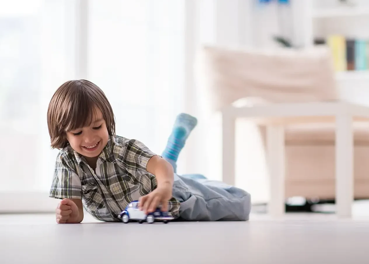 Young boy playing with a toy car on the living room floor