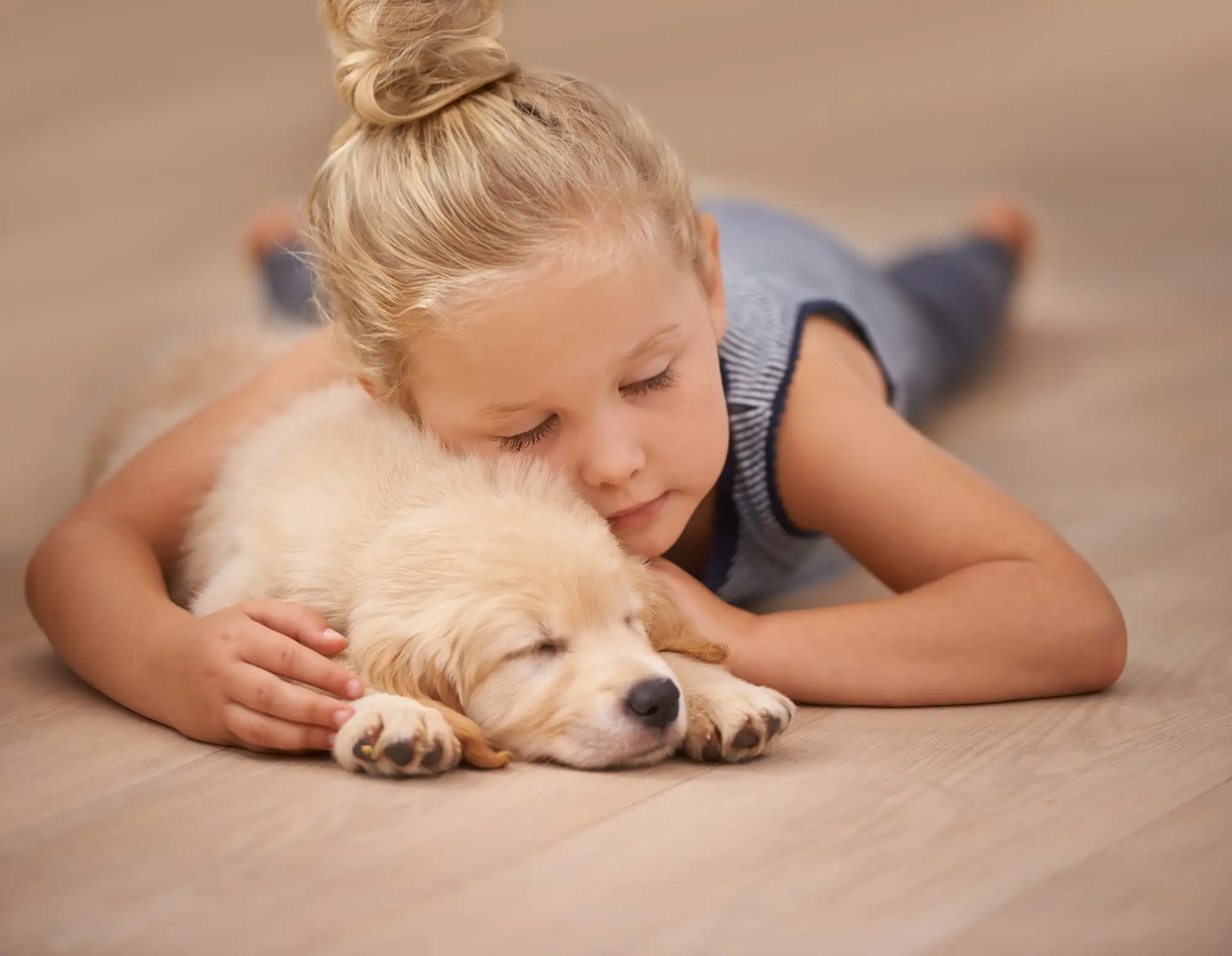 Girl asleep on a warm floor hugging a puppy