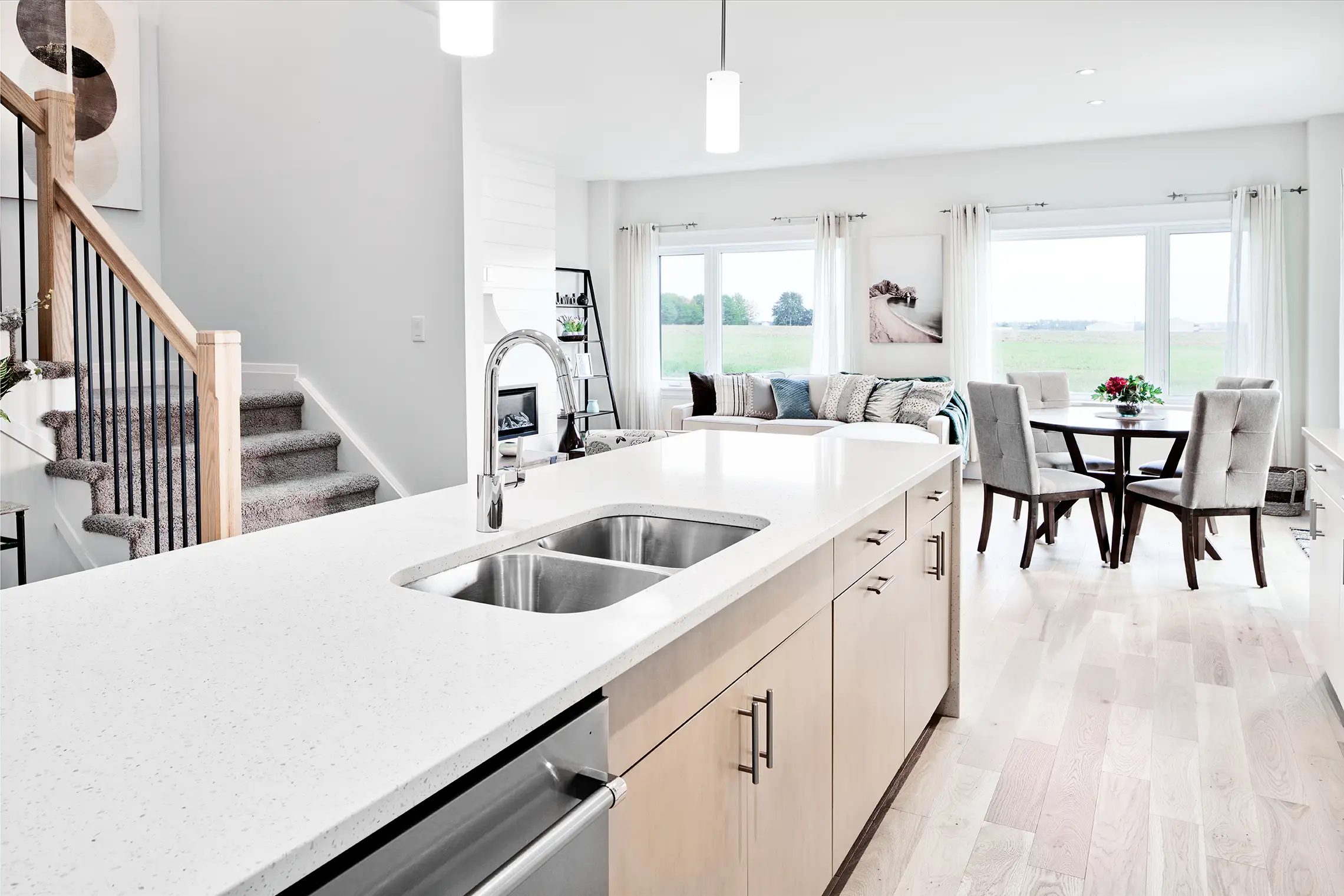Kitchen island with a double sink looking into an open-plan living and dining room